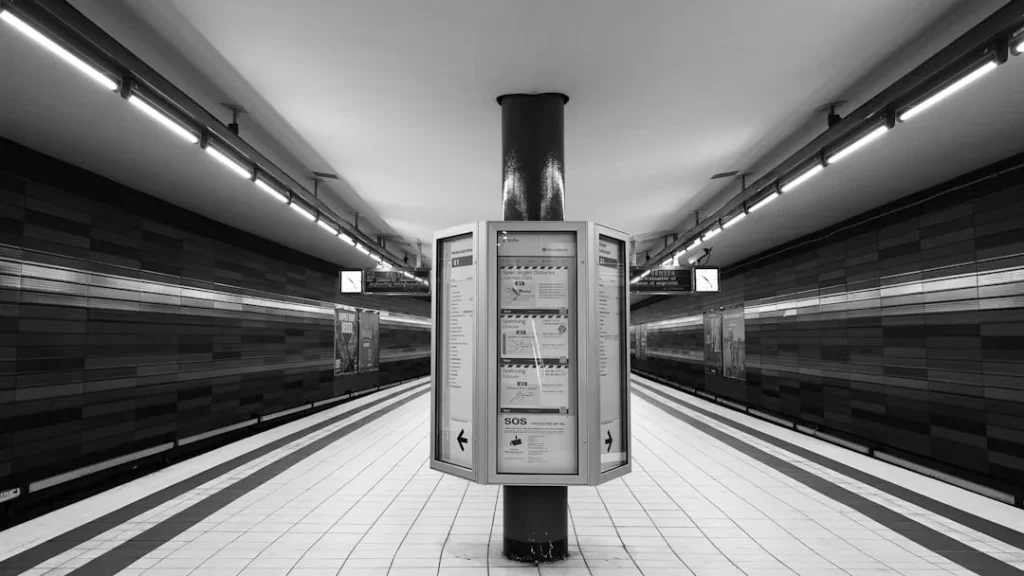 Empty subway station with tiled walls and lights.
