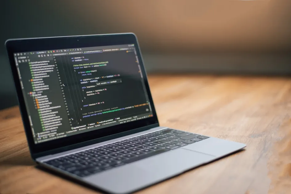 Laptop screen displaying lines of code on a wooden surface