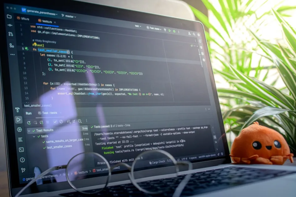 Laptop screen displaying code with glasses and plush toy