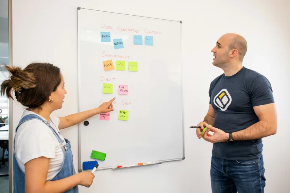 a man and a woman standing in front of a white board