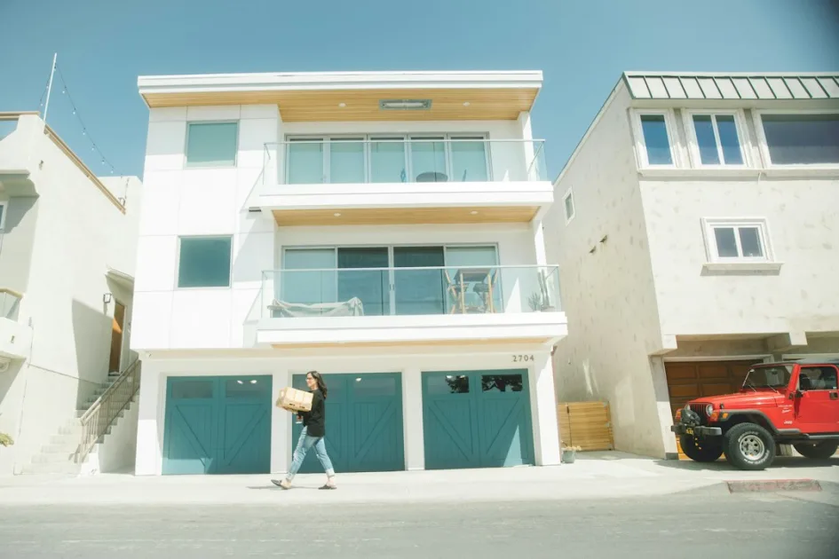 man in black t-shirt and blue denim jeans standing beside white concrete building during daytime