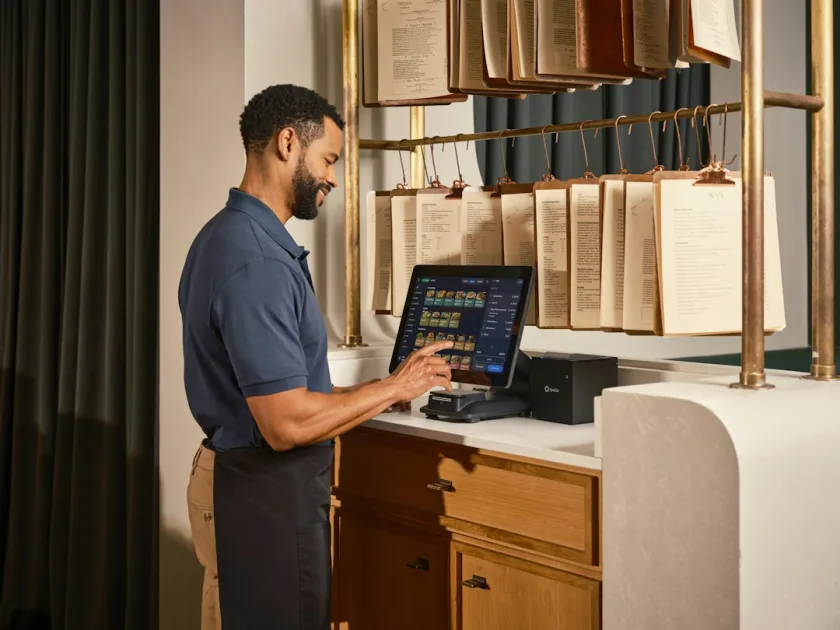Smiling man operates a point-of-sale system at a stylish counter