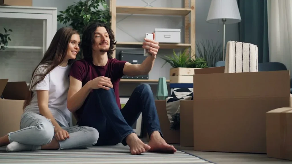 a man and woman sitting on the floor taking a selfie